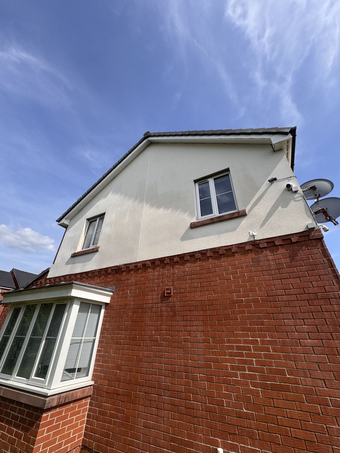Gable end render after softwash — clean uniform white render restored